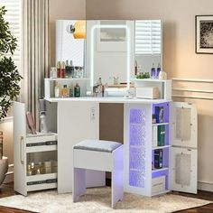 a white vanity with drawers and lights on it in a room next to a potted plant