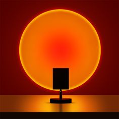 a black square lamp sitting on top of a table next to a red and yellow background