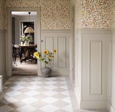 a vase with sunflowers sitting in the middle of a hallway next to a dining room table