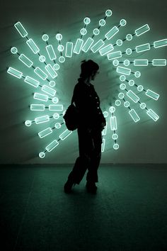 a person standing in front of a wall with neon lights on it's side