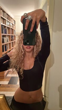 a woman taking a selfie with her cell phone in front of a bookshelf