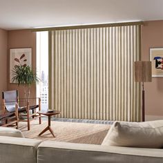 a living room with two couches and a large window covered in vertical blind blinds