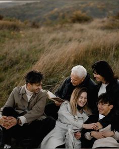 a group of people sitting next to each other on top of a grass covered field