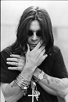 a man with long hair and sunglasses holding his hands to his face