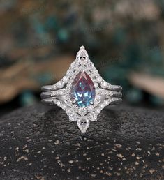 an engagement ring with a pear shaped blue topazte surrounded by diamonds