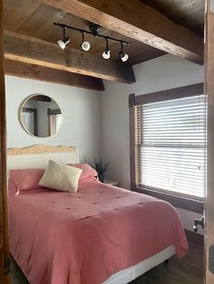 a bed sitting under a window next to a wooden ceiling mounted light fixture in a bedroom