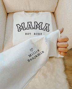 a woman's arm wrapped in a white blanket with the word mama printed on it