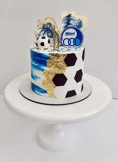 a soccer themed cake is on a white plate with gold foil and blue icing