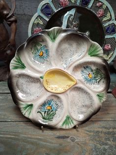 a ceramic dish with flowers painted on the front and sides, sitting on a wooden table