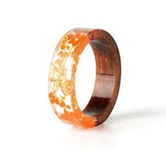 a wooden ring with an orange flower design on the outside and inside, against a white background