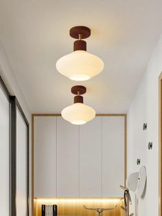 a long hallway with white walls and wooden flooring is lit by modern lighting fixtures