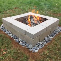 an outdoor fire pit in the middle of some grass with rocks and gravel around it