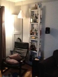 a living room filled with furniture and a book shelf next to a window covered in bottles