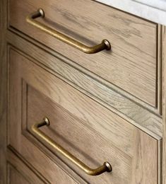 a wooden dresser with brass handles in a bathroom setting, close up view from the bottom