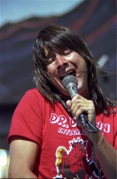 a man with long hair singing into a microphone