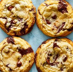 four chocolate chip cookies sitting on top of a blue surface