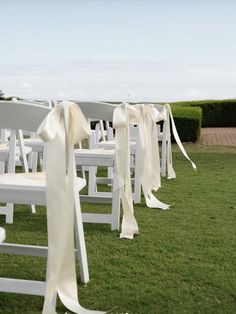 rows of white chairs with bows tied to them