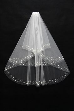 a white veil with pearls on the bottom and a bow at the top is hanging from a black background