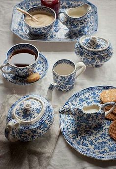 the table is set with blue and white dishes, cups, and saucers on it