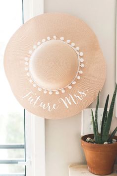 a hat is hanging on the wall next to a potted succulent plant