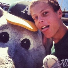 a young man poses with a stuffed animal in front of a baseball cap on his head