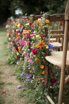 a row of wooden chairs sitting next to each other covered in flowers