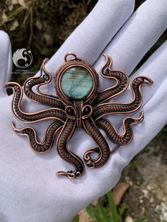 an octopus brooch with a stone in it's center sitting on a glove