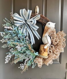 a wreath on the front door is decorated with blue and white ribbons, pine cones, and a bird figurine