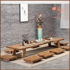 a wooden table with benches in front of a brick wall and vase filled with flowers