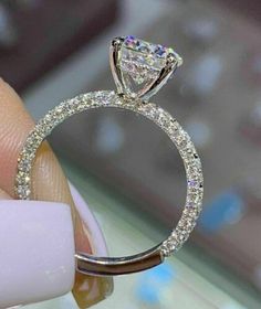 a woman's hand holding an engagement ring with diamonds on the inside and outside