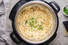 a pot filled with pasta and parsley on top of a table next to a cutting board