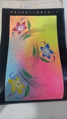 an artistically designed piece of paper with flowers painted on the inside of it, sitting on a chair