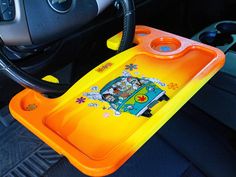 an orange tray with cartoon characters on it sitting in the passenger seat of a car