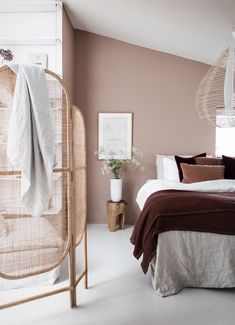 a bedroom with pink walls and white flooring is pictured in this image, there is a rattan headboard next to the bed