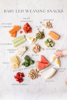 a baby is sitting in front of a variety of snacks on a white surface with the words, baby led weaning snacks