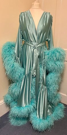 Beautiful chiffon dressing gown in Lagoon Breeze.  100% silk satin trimmed along the hem and the sleeve edges with luxurious ostrich feathers.  Fastens around the waist with a matching silk belt.  One size fits all due to the design, fullness and fabulousness of the robe.  Perfect for family gatherings, walking the dogs as well as taking out the rubbish. Please expect some feathers to shed - no one can look this fabulous without losing a few feathers. Long Sleeve Feather Robe For Parties, Elegant Satin Robe With Feathers, Elegant Feathered Evening Robe, Satin Dresses With Feather Trim, Elegant Party Robe With Feather Trim, Walking The Dogs, Satin Dressing Gown, Feather Gown, Feather Coat