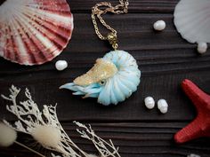 a necklace that is sitting on top of a wooden table next to shells and seashells