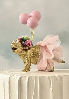 a cake topped with a gold dog and balloons