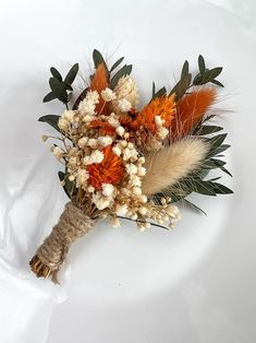 an arrangement of dried flowers and leaves on a white surface