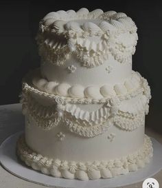 a three tiered white wedding cake with ruffles