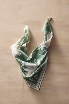 a green and white scarf laying on top of a wooden table