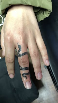 a person's hand with a snake tattoo on the middle finger and an arrow in the middle