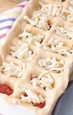 an uncooked pizza sitting on top of a blue and white striped towel with toppings