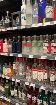 many bottles of alcohol are on display in a liquor store, including vodka and gin