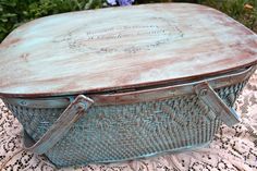 an old blue metal box sitting on top of a doily covered table with flowers in the background