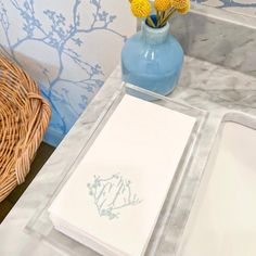 a blue vase with yellow flowers sitting on a marble counter top next to a white sink