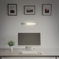 a computer monitor sitting on top of a desk next to a potted green plant