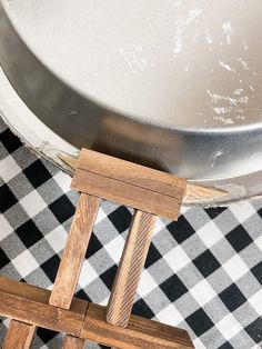 a wooden easel sitting on top of a checkered floor next to a metal pan