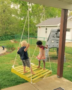 two young children playing on a yellow swing