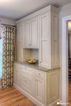 a kitchen with white cabinets and marble counter tops